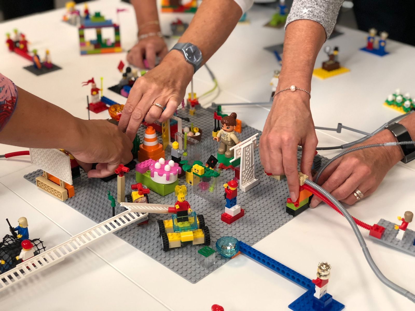 Varias personas construyen juntas un modelo con piezas LEGO sobre una mesa durante un taller